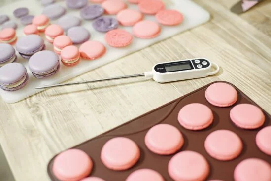 Digital thermometer next to macarons on tray