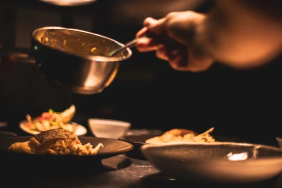 Person adding sauce to food on plate