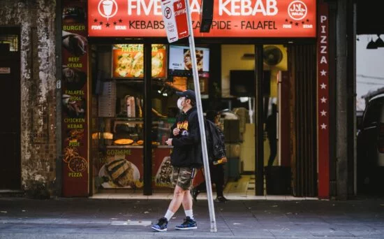 Person walking past kebab shop storefront