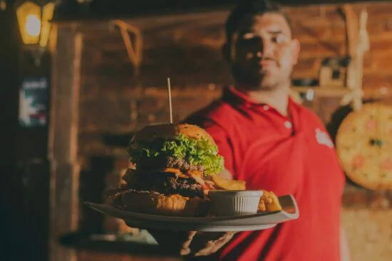 Server holding burger plate in restaurant