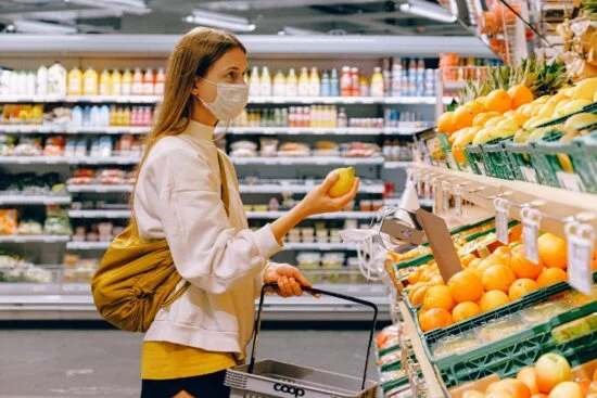 Woman wearing mask shopping for fruit in grocery store