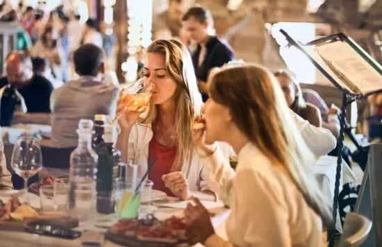 People eating and drinking at restaurant table