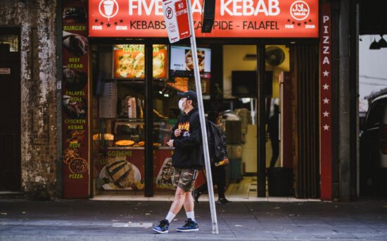 masked student waits at urban bus stop